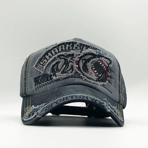 Detailed close-up of distressed denim baseball cap with shark embroidery and frayed edges
