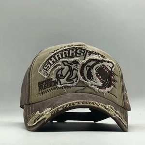 Close-up of distressed canvas baseball cap featuring shark embroidery and worn-out details