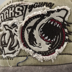 Detailed macro view of khaki cotton baseball cap with shark patch and embroidery