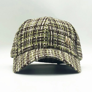 Detail of tweed baseball cap showing green weave and gold M logo with rhinestones