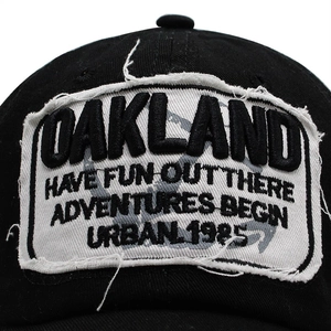 Close-up of Oakland embroidery patch on black cotton baseball cap with distressed edges