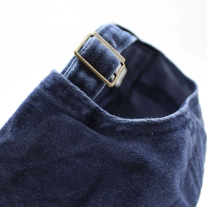 Detailed macro view of the vintage brass buckle and corduroy strap on baseball cap