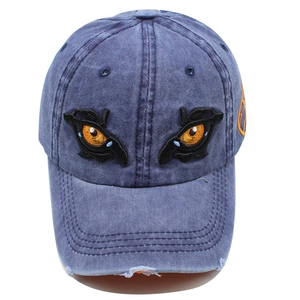 Detailed embroidery of eyes and orange circle on a distressed wash denim baseball cap