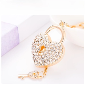 Detailed macro view of heart-shaped gold lock keychain with inlaid white rhinestones