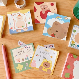 Detailed view of cute bear memo pads and stationery on a light wooden desk