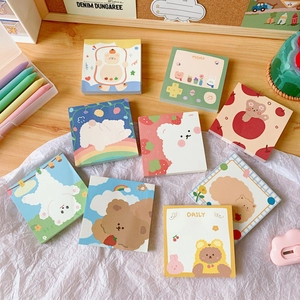 Flat lay of colorful cartoon bear and rabbit memo pads on a cozy wooden desk