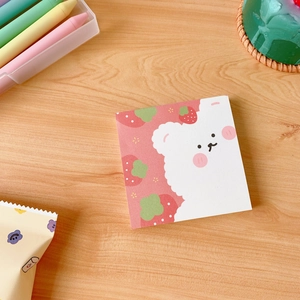 Close-up of cute strawberry and white bear memo pad on a wooden desk setting