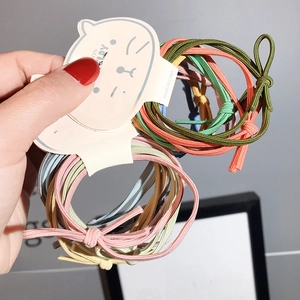 Dettaglio di sei elastici per capelli colorati con nodo su supporto a forma di gatto