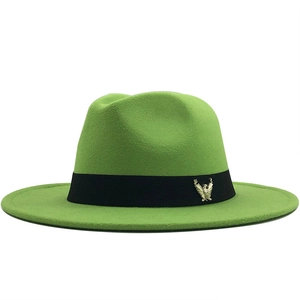 Close-up of emerald green wool fedora hat featuring a black ribbon and gold eagle pin