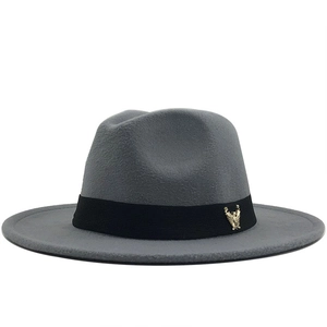 Detail of grey wool fedora hat featuring a black ribbon and gold eagle badge