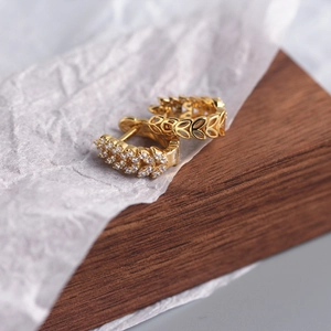 Detailed close-up of golden S925 silver hoop earrings with hollow leaf and zircon inlay