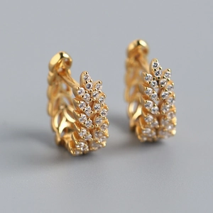 Macro shot of gold leaf earrings with sparkling clear cubic zirconia on a gray background