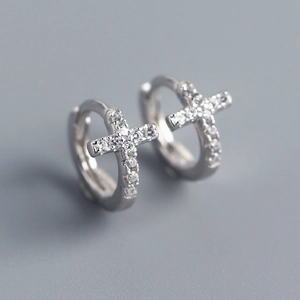 Macro shot of silver S925 cross earrings with sparkling zircons on a gray background