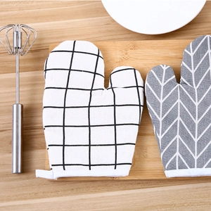 Heat resistant oven mitts with black grid and grey herringbone patterns on wooden board