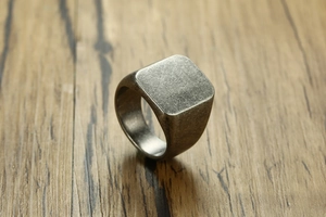 Macro shot of industrial square signet ring with vintage silver finish on wood texture