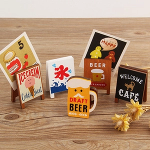 Miniature wooden cafe signs and ice cream cards displayed on a rustic wood surface