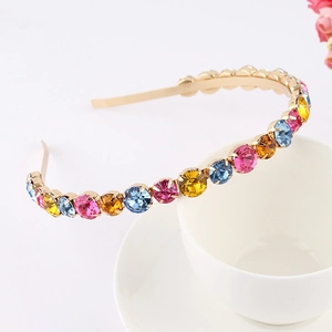 Close-up of colorful rhinestones on a gold metal headband resting on a white cup