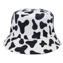 Detailed view of bucket hat featuring classic black and white cow print pattern on white