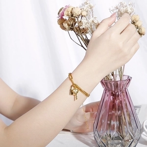 Gold titanium steel chunky chain bracelet with heart, lock and key charms worn by model