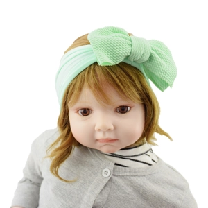 Close-up of a pale green baby headband with a large fabric bow on an infant model