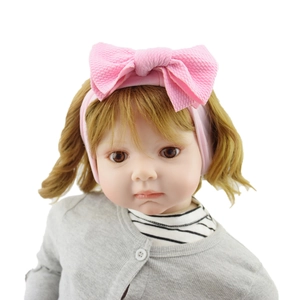 Close-up of baby girl reborn doll wearing a large pink knotted bow headband