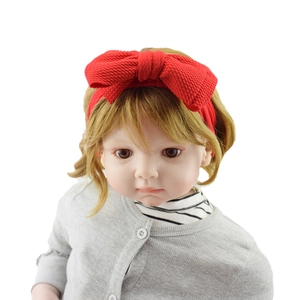 Detail shot of a baby model wearing a red oversized bow headband made of soft fabric