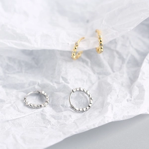 Detailed view of gold and silver beaded S925 sterling silver hoop earrings on white paper