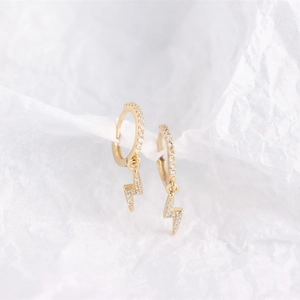 Macro shot of gold plated lightning bolt earrings with shimmering zircon stones