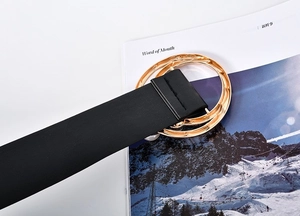 Détail d'une ceinture noire en similicuir avec boucle dorée à double anneau sur magazine