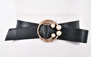 Détail d'une large ceinture noire avec boucle dorée ornée de quatre perles blanches