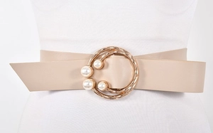 Détail d'une ceinture en similicuir kaki avec une boucle ronde dorée et trois perles