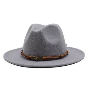 Detail of grey wool fedora hat with brown leather band and metallic skull ornament
