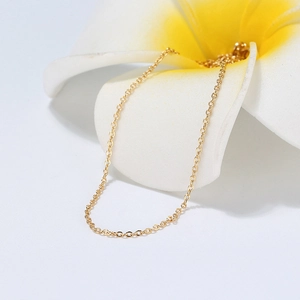 Detailed view of a gold s925 sterling silver cable chain resting on a frangipani flower