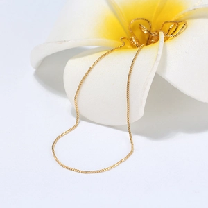 Detailed view of a slender golden S925 sterling silver box chain on a white flower blossom