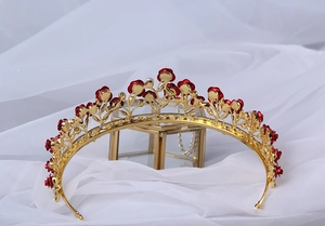 Detailed back view of a gold bridal crown with delicate red rose elements on white silk