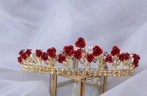 Detailed shot of golden bridal crown featuring red roses, crystal rhinestones and pearls