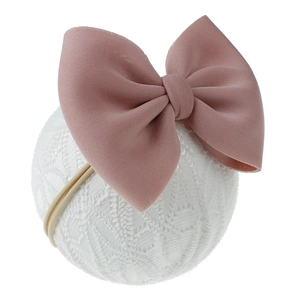 Détail du bandeau bébé avec nœud rose poudré en tissu sergé sur une boule de dentelle