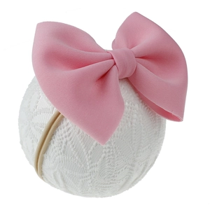 Vue détaillée de la texture du tissu d'un grand nœud rose sur un bandeau pour bébé