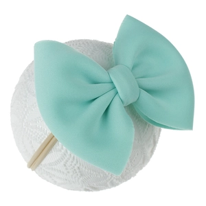 Détail du bandeau bébé avec grand nœud en tricot vert menthe et élastique de couleur chair