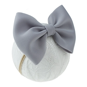 Détail d'un bandeau bébé à nœud gris en tissu sur un support en dentelle blanche