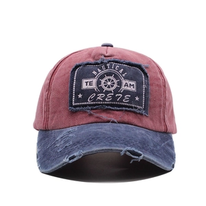 Detail of nautical embroidery and distressed brim on wine red and navy baseball cap