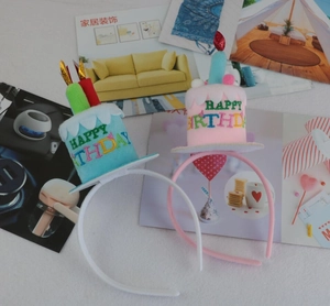 Detailed view of pink and blue plush birthday cake headbands with candles and embroidery