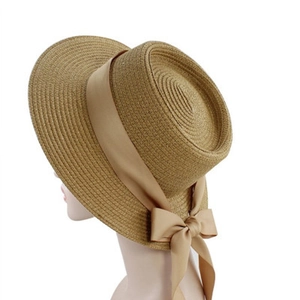 Detail view of woven straw boater hat featuring an elegant beige ribbon bow on the side