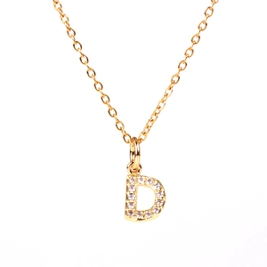 Detailed macro view of a gold-plated necklace with a diamond-encrusted letter D pendant