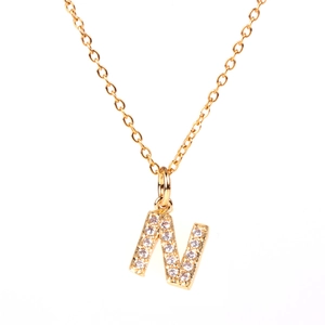 Macro shot of gold letter N pendant with micro-pave crystal inlay and fine gold chain