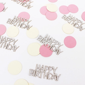 Flat lay of silver Happy Birthday glitter confetti with pink and cream paper circles