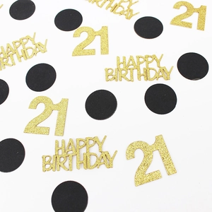 Close-up of gold glitter Happy Birthday and 21 confetti with black circles on white