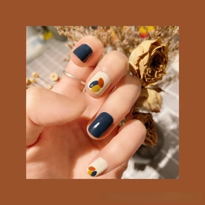 Close-up of modern abstract 3D nail stickers in navy blue, yellow, and beige tones