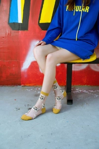 Detail of sheer cat print mid-calf socks with yellow accents on a street style background