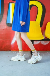 Close-up of white chunky sneakers and cute cat pattern socks on a street model